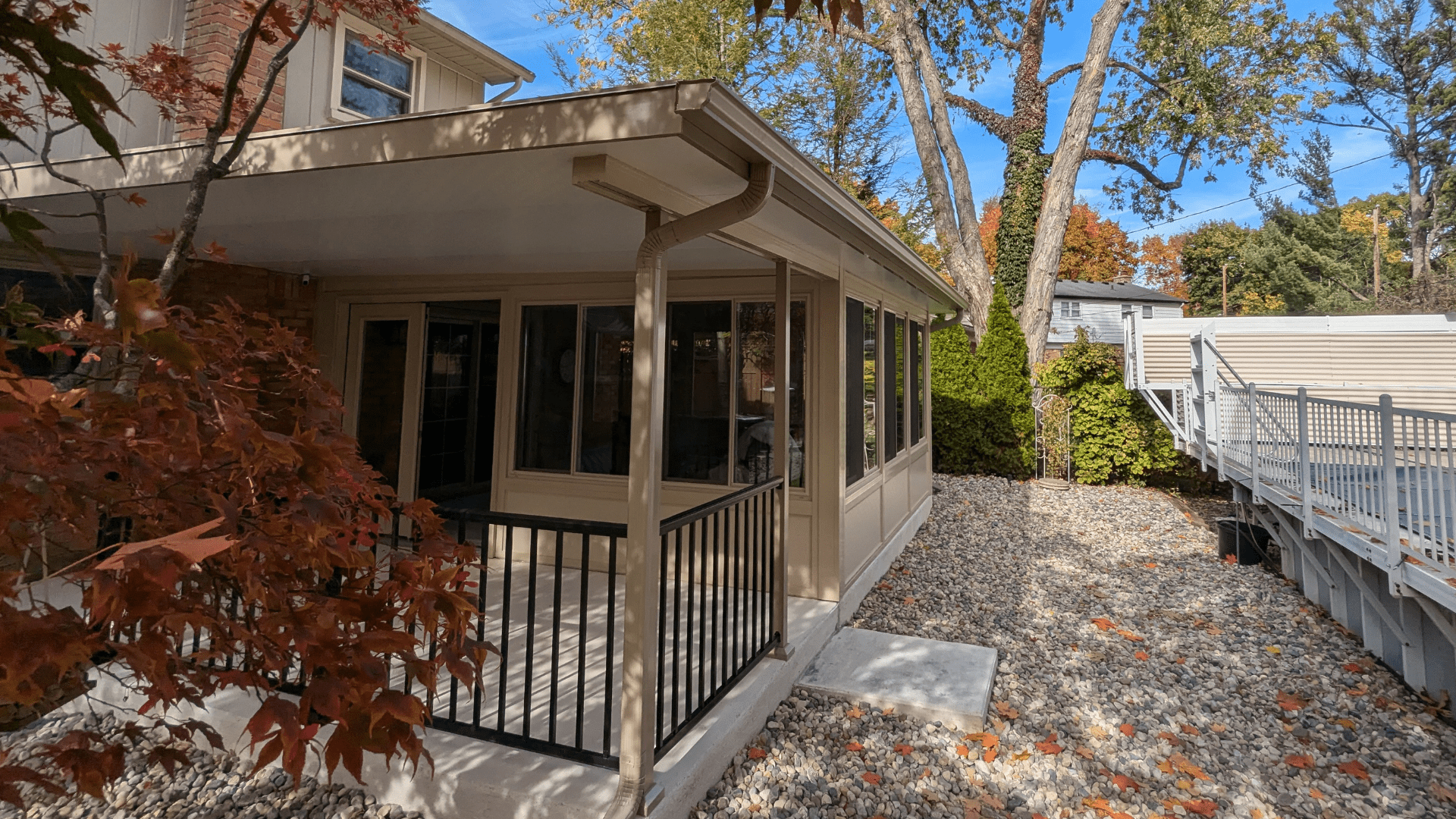 An elegant backyard patio enclosure surrounded by lush greenery, showcasing how patio enclosures increase property value and provide versatile outdoor living spaces
