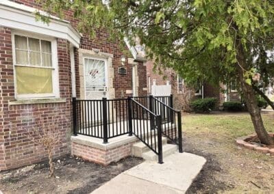 Red brick residential home with a black porch railing built by Wayne Craft