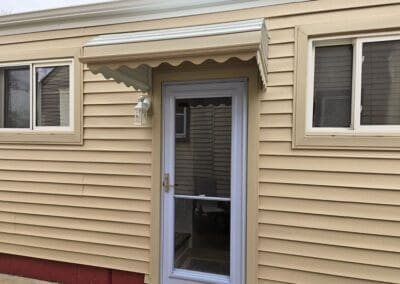 Michigan home with beige siding and a white aluminum door awning built by Wayne Craft