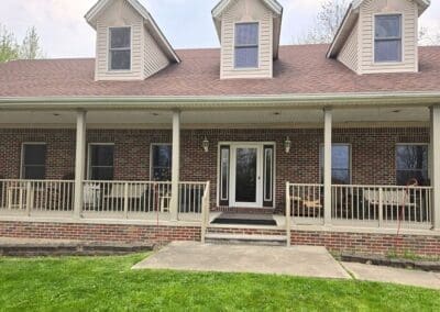 Wide front porch of a Michigan brick home with beige aluminum railings built by Wayne Craft