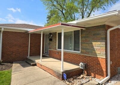 Side view of Michigan brick home with white aluminum awning accented with a red trim built by Wayne Craft