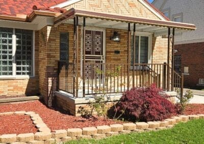 Side view of a Michigan brick home featuring a brown aluminum awning and railing built by Wayne Craft
