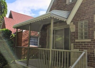 Side view of a Michigan brick home featuring a beige aluminum awning and railing built by Wayne Craft