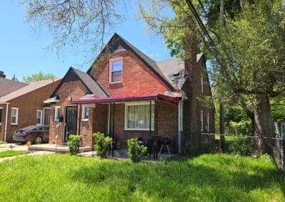 Front view of a red brick home featuring a red awning and black railing built by Wayne Craft