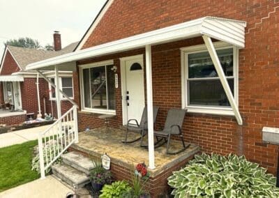 Red brick residential home with a white awning and porch railing built by Wayne Craft